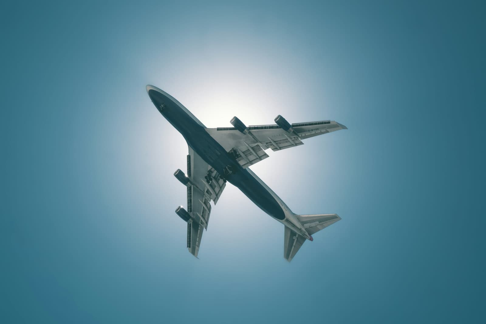 Wide-body cargo jet overhead against a bright sky